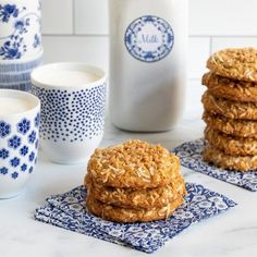 cookies and milk are sitting on the table next to each other, with blue and white dishes in the background