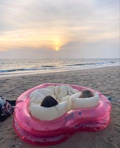 a person laying on an inflatable mattress at the beach