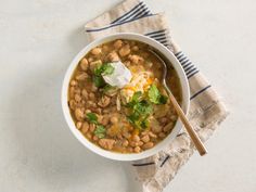 a white bowl filled with beans and sour cream on top of a blue striped napkin