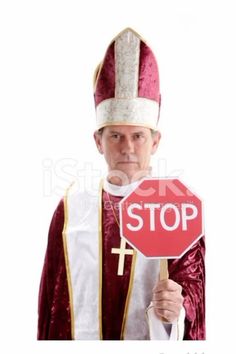 a man holding a stop sign in front of his face while wearing a priest's outfit