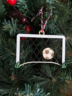 a christmas ornament with a soccer ball hanging from it's side on a tree