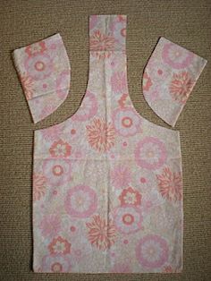 an apron made out of fabric with pink and white flowers on the front, sitting on a carpeted floor