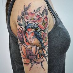 a woman with a bird and flowers tattoo on her arm