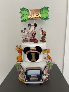 a three tiered cake decorated with mickey mouse and other disney characters on the top