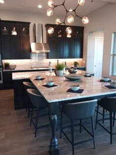 a large kitchen with black cabinets and marble counter tops