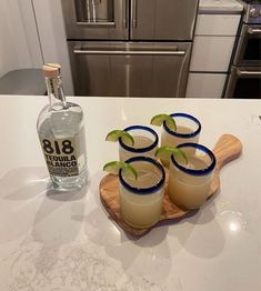 three glasses filled with drinks sitting on top of a counter next to an empty bottle