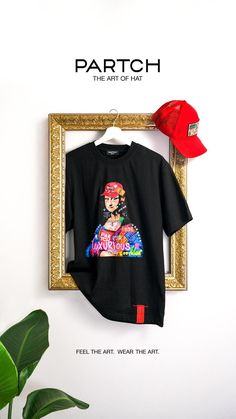 a t - shirt hanging up on a wall next to a plant and a hat