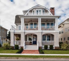 a white two story house with porches and balconies on the second floor