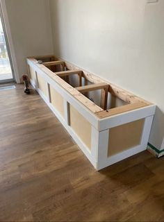 an unfinished window seat in the corner of a room with wood flooring and white walls