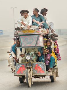 a group of people riding on the back of a truck down a street in india