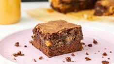 two pieces of brownie sitting on top of a white plate next to a glass of orange juice