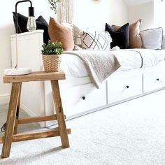 a living room filled with furniture and pillows on top of a white couch next to a wooden table