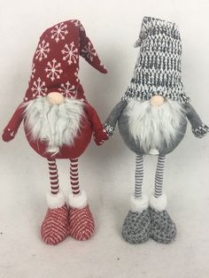 two knitted gnomes are standing next to each other on a white surface with snowflakes