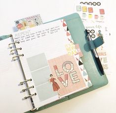 an open planner book sitting on top of a table next to a pen and clipboard