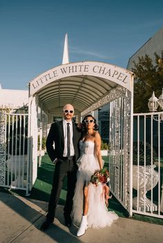 a man and woman standing in front of a white chapel