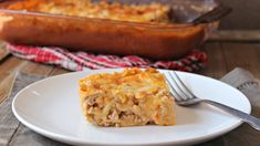 a piece of casserole on a white plate with a fork next to it