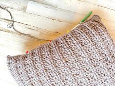 a crocheted pillow sitting on top of a wooden floor next to a pair of scissors