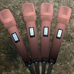 four pink microphones sitting on top of each other in front of a gray carpet