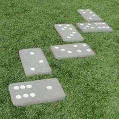 four pieces of cement with white dots on them sitting in the middle of some grass