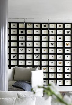 a living room filled with white furniture and lots of butterflies on the wall behind it