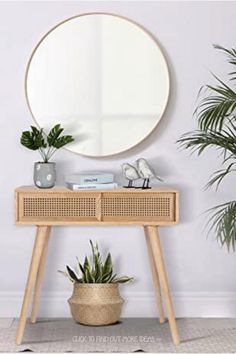 a round mirror sitting on top of a wooden table next to a potted plant