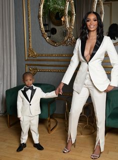 a woman in a white suit holding hands with a small child