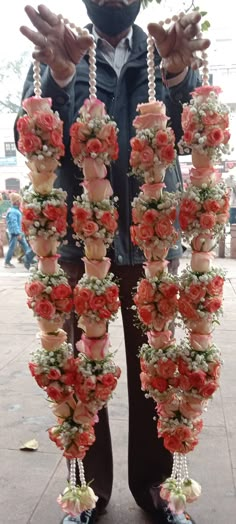 a man standing next to a bunch of fake flowers on a string with his hands in the air