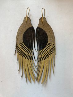 two pairs of gold and black leather earrings with fringes on the ends, hanging from hooks