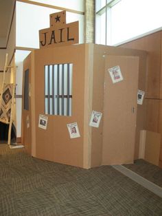 a cardboard jail cell in an office cubicle with pictures taped to the walls and doors