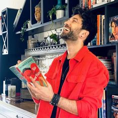 a man standing in front of a bookshelf with his mouth open and holding a book