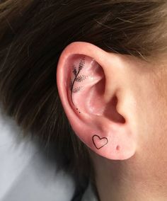 a person with a small tattoo on their ear and behind the ear is a leaf