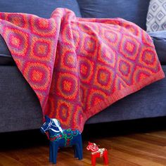 a blue couch sitting next to a red and pink blanket on top of a wooden floor