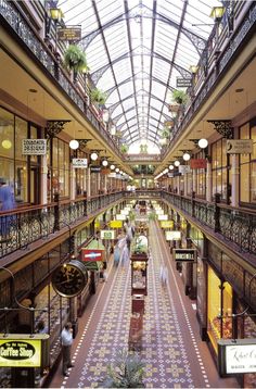 an indoor shopping mall filled with lots of shops and people walking through the walkways