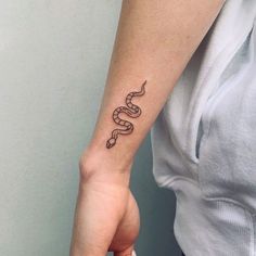 a woman's arm with a snake tattoo on the left side of her wrist