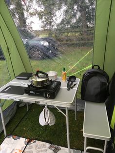 a camper's tent with a stove and backpack on the table