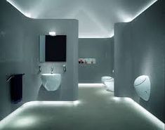 a modern bathroom with two sinks and three urinals on the wall, all lit up by lights