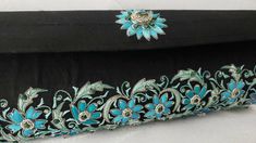 "The perfect wedding purse! A sophisticated and feminine black silk clutch bag, expertly hand embroidered by zardozi artisans. A profusion of petit blue silk flowers are inlaid with emerald gemstones. Each delicate petal and leaf is meticulously outlined with a glittery silver metallic thread, to give a sparkly, opulent 3D effect. Crowned by a beautifully embroidered blue medallion with an emerald cabochon. The word Zardozi means \"gold thread\". It is an elaborate and intricate embroidery art f Elegant Black Hand Embellished Clutch, Elegant Black Hand-embellished Clutch, Black Hand Embellished Clutch For Wedding, Traditional Black Evening Bag For Wedding, Handmade Black Evening Bag For Wedding, Traditional Black Wedding Bag, Black Clutch With Handwork For Wedding, Elegant Formal Clutch With Intricate Embroidery, Rectangular Wedding Clutch With Resham Embroidery