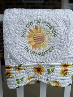 a close up of a white quilt with sunflowers on it and the words, my sunshine is here