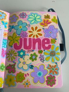 an open book with flowers and the word june written in pink, blue, yellow and green