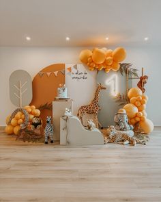 an animal themed birthday party with orange balloons and giraffes on the wall