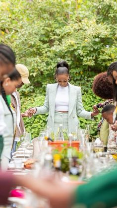 a group of people standing around a table with food and drinks on top of it