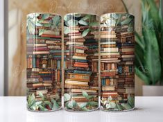 three coffee mugs with books on them sitting on a table next to a potted plant