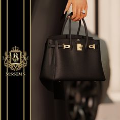 a woman's hand holding a black purse