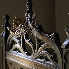 an ornate metal headboard and foot board with gold crown decorations on the top part