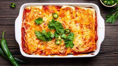 a casserole dish with cheese, sauce and green peppers on a wooden table