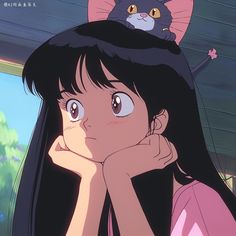 a girl with long black hair and a cat on her head looking at the camera