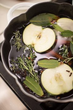 apples and herbs cooking in a skillet on the stove top with oil over them