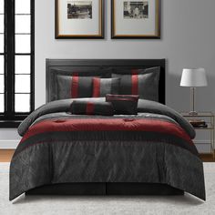 a bed with red and black comforters in a room next to two framed pictures