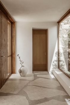 a large white vase sitting in the middle of a hallway next to a wooden door