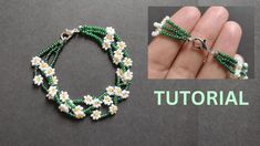 a hand holding a green and white beaded bracelet with daisies on the end